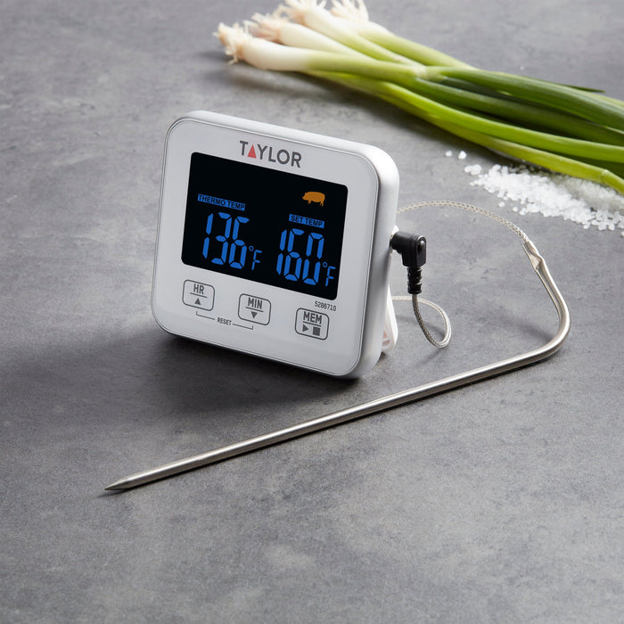 Taylor digital wired thermometer on a gray countertop with fresh leeks in the background