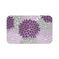 A rectangular memory foam mat with a muted color scheme consisting of a purple, light purple, and light gray floral pattern against a white background, with anti-slip backing.