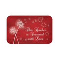 A red rectangular kitchen memory foam mat with white text and dandelion designs, and the phrase 'This Kitchen is Seasoned with Love'.