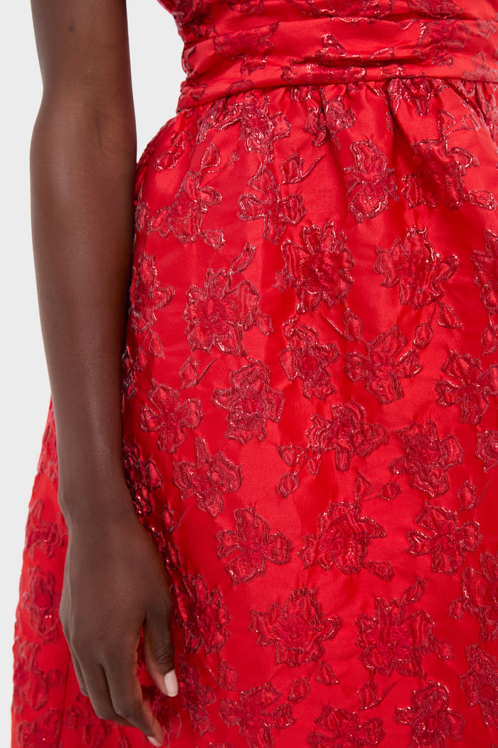 A person wearing a red Saylor dress with textured floral embroidery; only the torso and one arm are visible against a plain background.