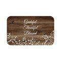 A rectangular brown memory foam mat with the text 'Grateful Thankful Blessed' printed on it, featuring a floral pattern around the edges.