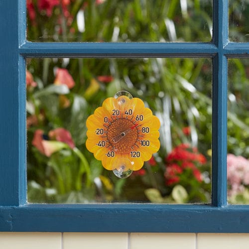 Yellow sunflower shaped silicone thermometer mounted on a blue window with suction cups