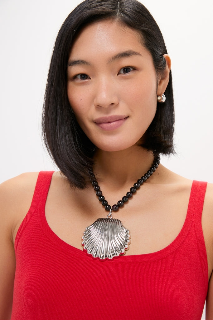 Silver Holbox Necklace: A classic, chunky black beaded necklace featuring an effortless, high-end shell-shaped silver pendant, perfect for adding fun elegance to any outfit.