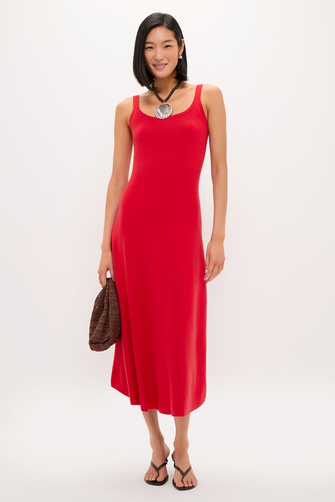 Woman wearing classic Silver Holbox Necklace with bold shell-shaped pendant, complementing a red dress; she holds a woven handbag, embodying effortless, high-end style.