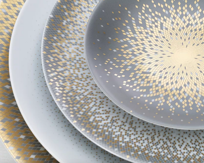 Four overlapping Haviland Souffle D'or Limoges porcelain plates, arranged from largest to smallest, feature intricate gold and silver concentric squares and dotted geometric patterns radiating from the center.