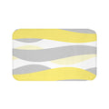 A rectangular yellow and gray abstract waves patterned memory foam mat with anti-slip backing.