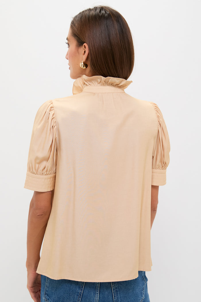 Woman in Tan & Cream Embroidery Louisa Blouse, showcasing a classic, effortless style with a ruffle collar and puff sleeves, paired with blue denim, exuding high-end elegance.