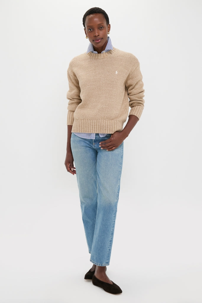 Woman showcases the Tan Heather Cotton Long Sleeve Crewneck, layered over a striped shirt with jeans and flats, highlighting its classic, effortless, and high-end style.