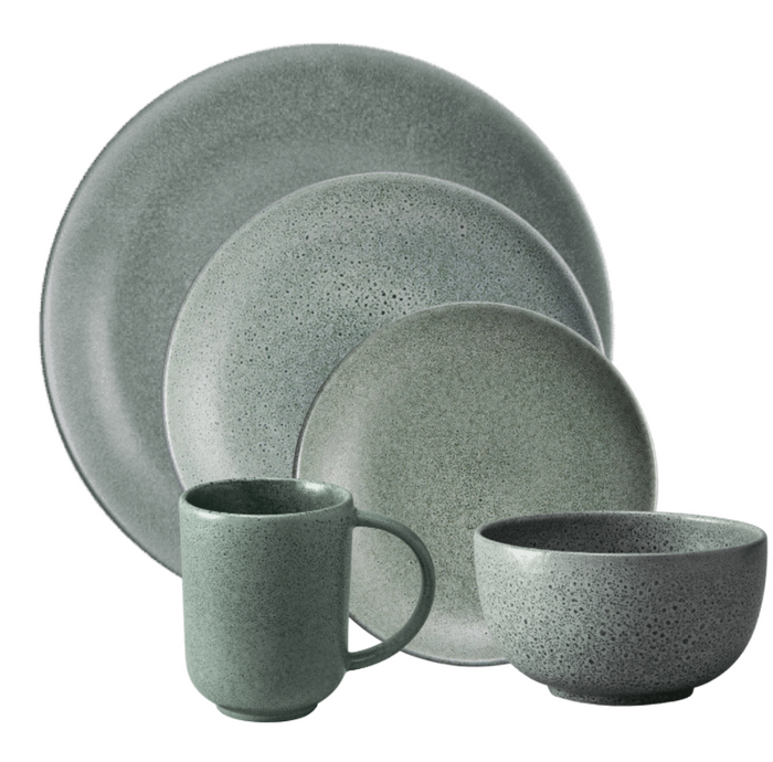 The L'Objet Terra Seafoam Dinnerware set in muted green features a dinner plate, salad plate, bowl, and mug with a speckled matte finish and minimalist design, arranged overlapping each other.