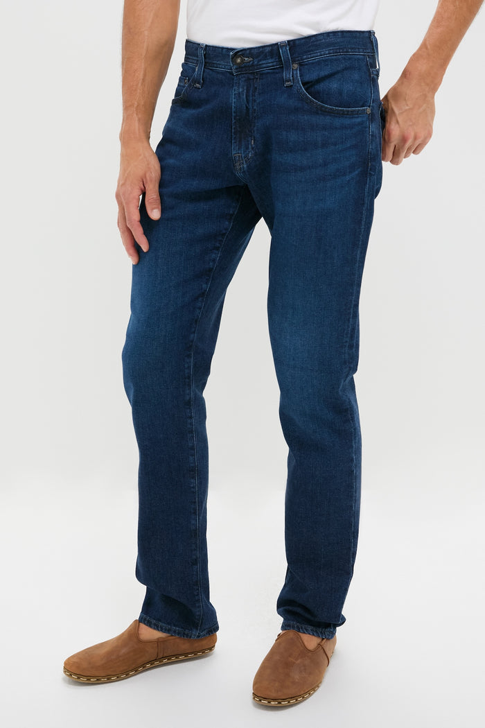 The Graduate in Crusade Wash Denim, showcasing classic, effortless style with a slim, relaxed fit and high-end craftsmanship, paired with brown slip-on suede shoes.
