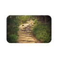 The image on this memory foam floor mat is of a stone pathway leading down a trail with tall grasses and trees on either side. The image has been brightened to make the pathway's dirt and stone steps pop out.