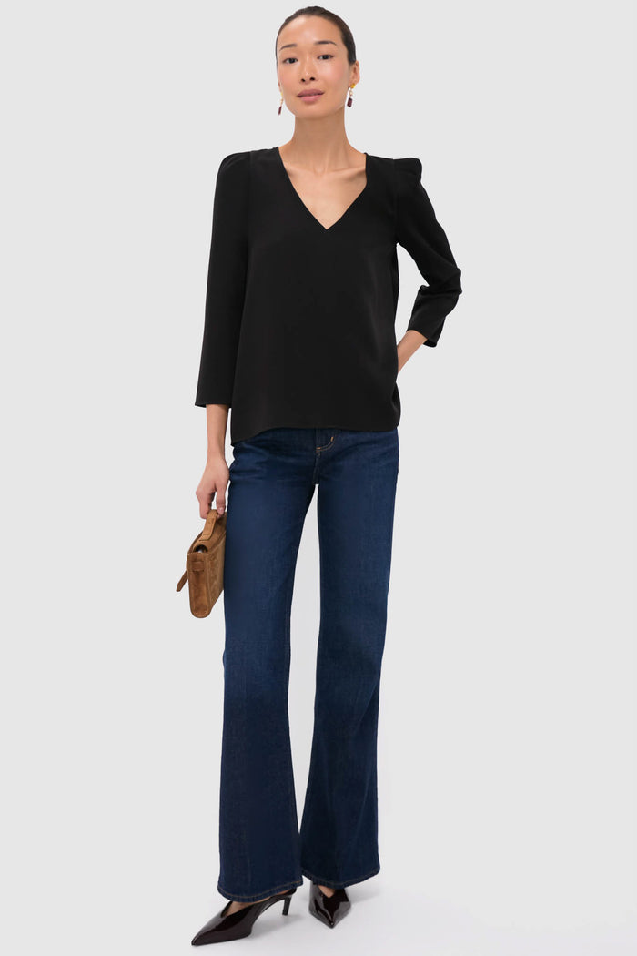 Model showcases an effortless, classic style with the Wine Allie Earrings, featuring colorful stones in sparkling drops, alongside a black blouse and dark indigo jeans.